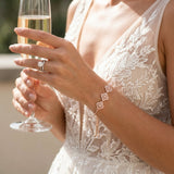 Bride wearing the Addia rose gold cubic zirconia bracelet with adjustable slider closure while holding a champagne flute, showcasing elegant bridal wrist jewelry.