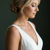 Side view of bride wearing the Emma gold CZ lariat bridal necklace with delicate drop and V-neck wedding dress.