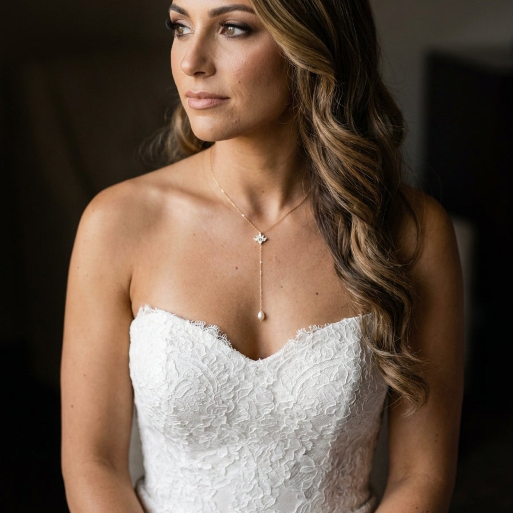 Bride wearing the Emma dainty gold CZ lariat necklace with a delicate drop and strapless lace wedding gown.
