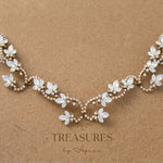 Antique gold Cleo bridal hair vine adorned with Swarovski white opal crystal flowers and sparkling curved scrollwork, displayed with hair combs on a branded card.