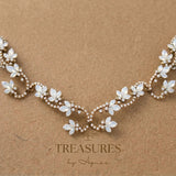 Antique gold Cleo bridal hair vine adorned with Swarovski white opal crystal flowers and sparkling curved scrollwork, displayed with hair combs on a branded card.