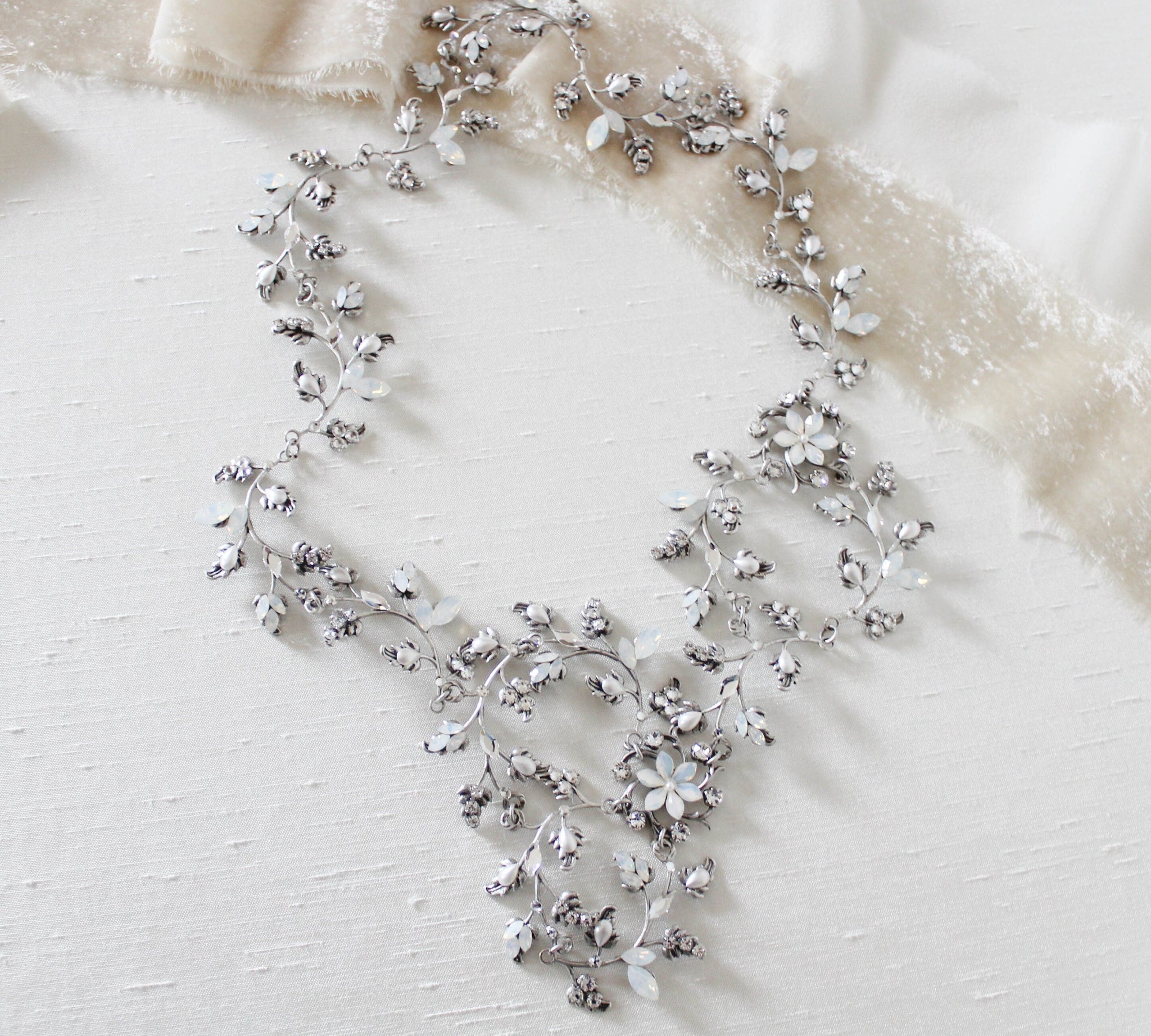Treasures by Agnes Abigail handcrafted bridal hair vine featuring Swarovski white opal crystals, crystal flowers, and a flexible silver vine design displayed on ivory fabric.