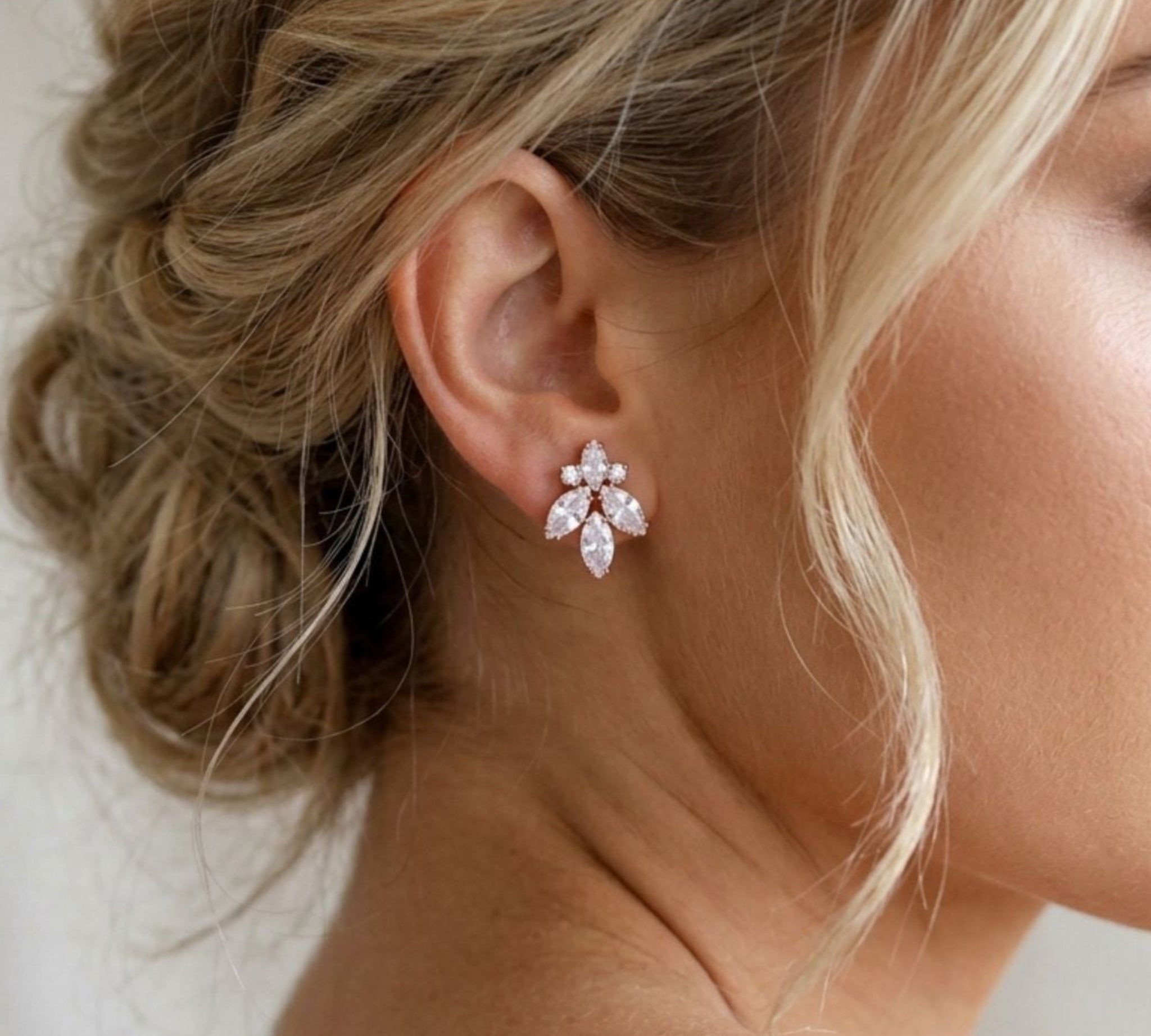 Bride wearing Divine bridal stud earrings featuring sparkling cubic zirconia marquise and pear stones in a delicate cluster design