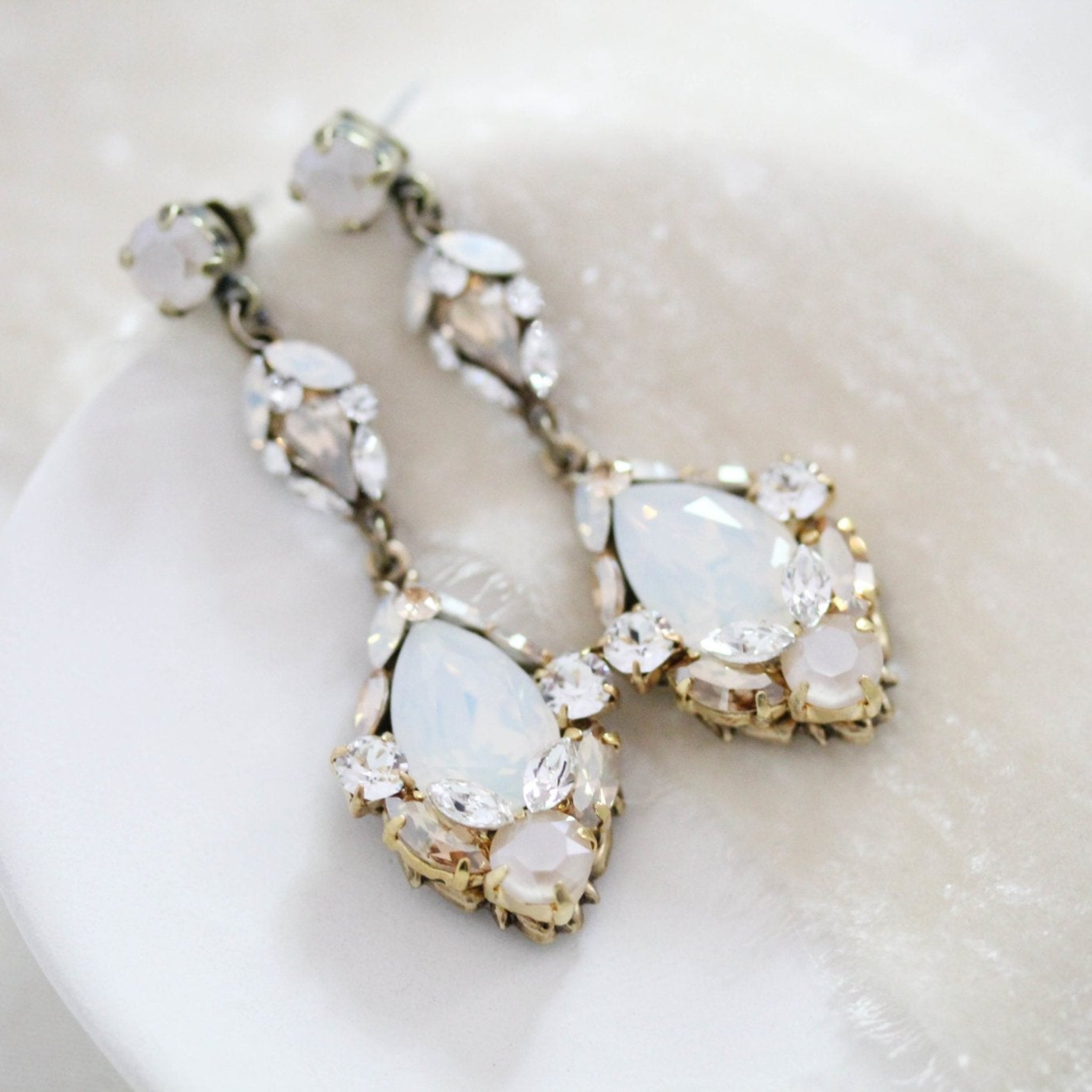 Skylar Swarovski crystal teardrop earrings displayed on soft ivory fabric